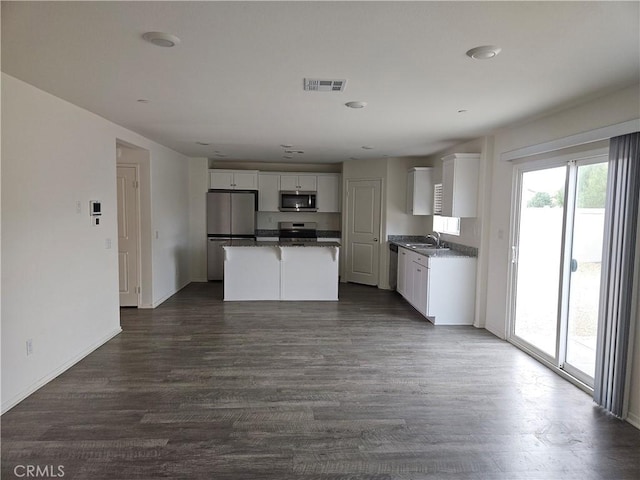 kitchen featuring stainless steel appliances, a center island, dark wood-type flooring, white cabinets, and sink