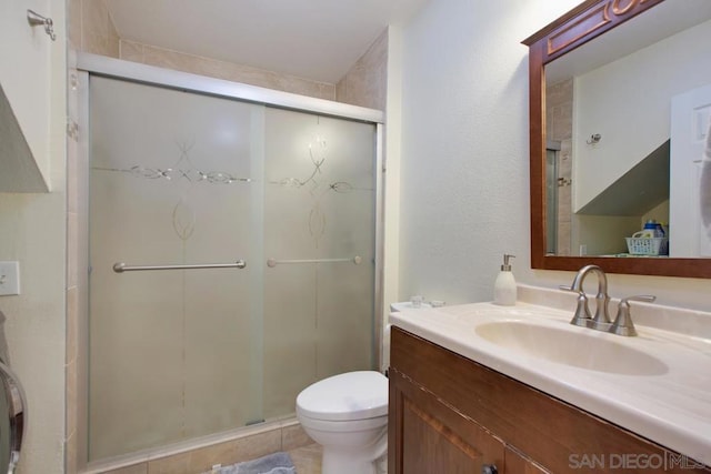 bathroom featuring vanity, a shower with shower door, and toilet