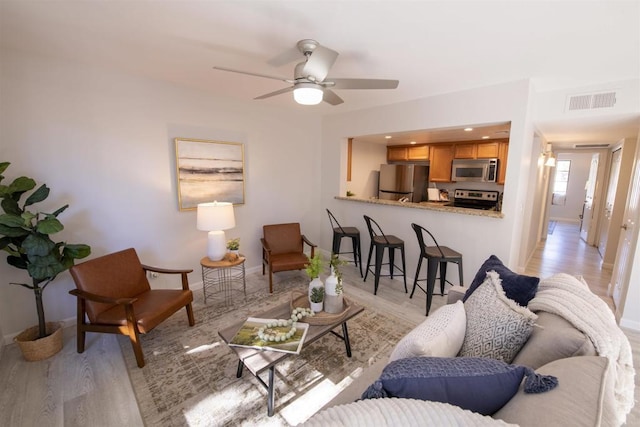 living room with ceiling fan and light wood-type flooring