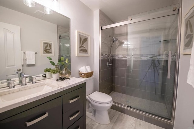 bathroom with vanity, hardwood / wood-style floors, a shower with shower door, and toilet