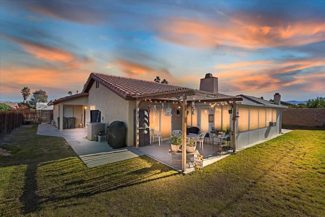 back house at dusk with a patio area and a yard