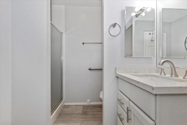 bathroom featuring toilet, a shower with door, and vanity