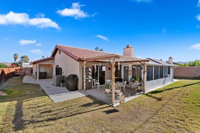 back of property featuring a lawn, a patio area, and a sunroom