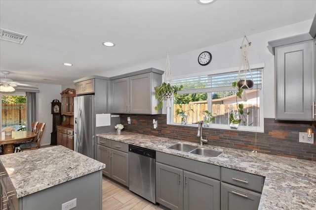 kitchen featuring light stone counters, sink, stainless steel appliances, and tasteful backsplash