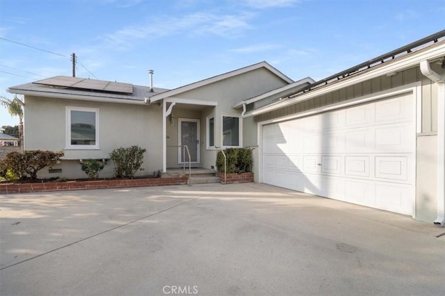 ranch-style home with a garage and solar panels