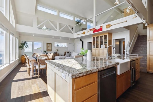 kitchen featuring dishwasher, sink, a kitchen island with sink, high vaulted ceiling, and light stone counters