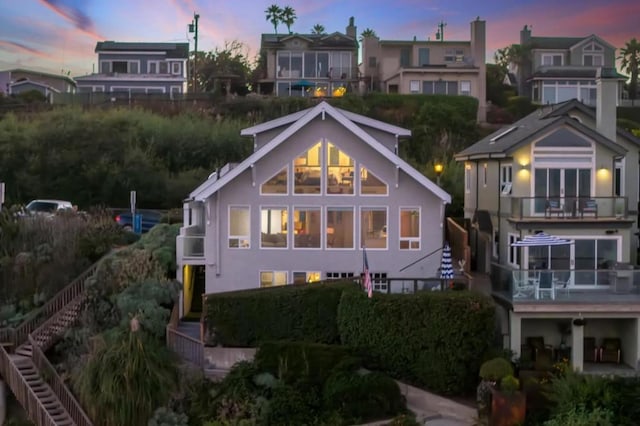 back house at dusk featuring a balcony