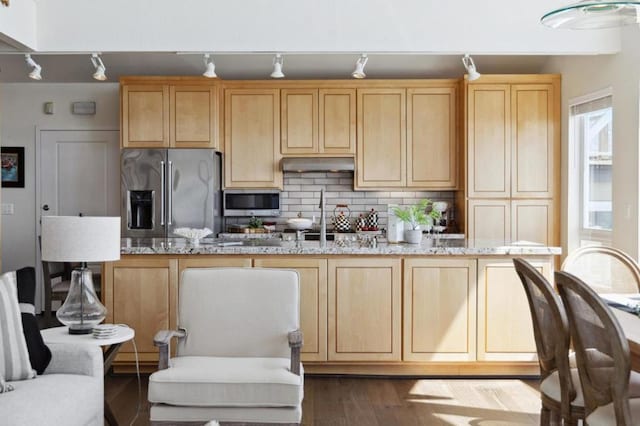 kitchen featuring tasteful backsplash, hardwood / wood-style flooring, light stone countertops, appliances with stainless steel finishes, and light brown cabinetry