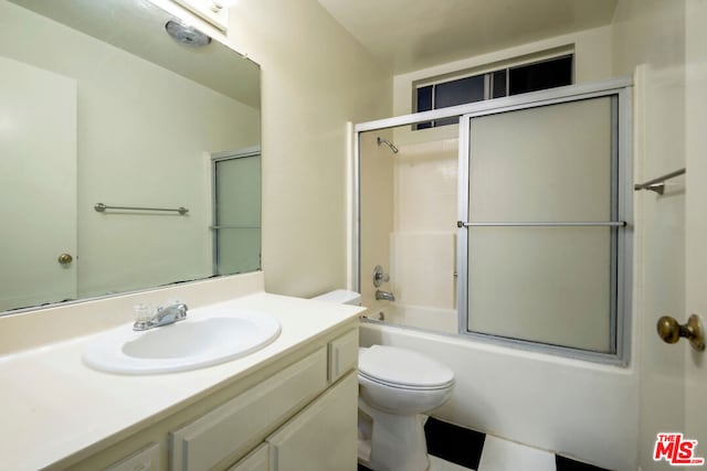 full bathroom featuring toilet, bath / shower combo with glass door, and vanity