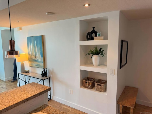 corridor featuring built in shelves and light hardwood / wood-style flooring