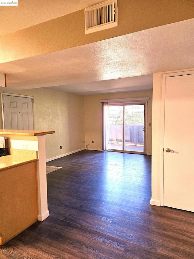 unfurnished living room with dark wood-type flooring and a textured ceiling