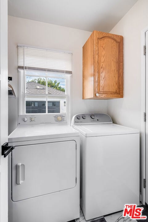 clothes washing area with washing machine and dryer and cabinets