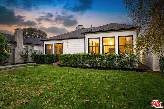 back house at dusk featuring a yard