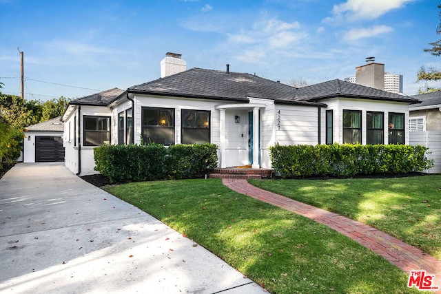 bungalow-style home with a front yard, an outdoor structure, and a garage