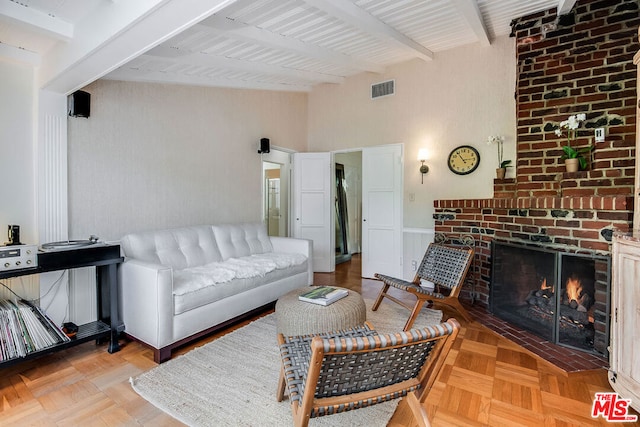 living room featuring beam ceiling, a fireplace, and light parquet floors