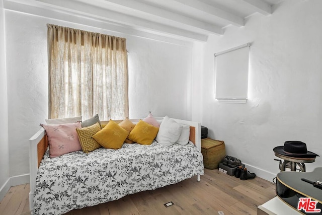 bedroom featuring beam ceiling and light hardwood / wood-style flooring