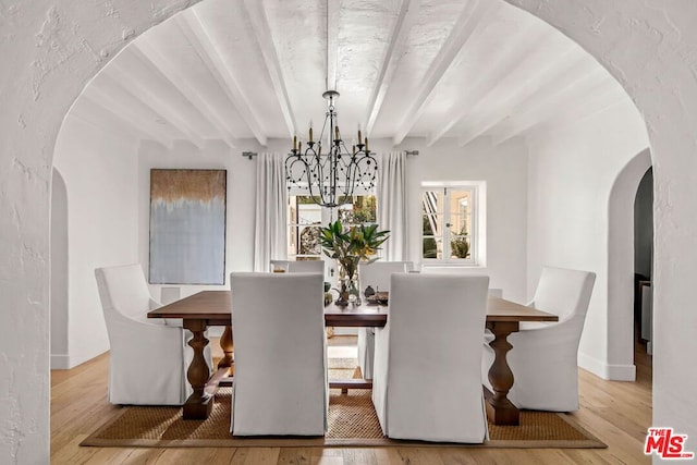 dining space with an inviting chandelier, beamed ceiling, and light wood-type flooring