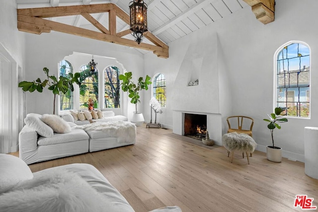 living room featuring a large fireplace, a healthy amount of sunlight, high vaulted ceiling, and beamed ceiling