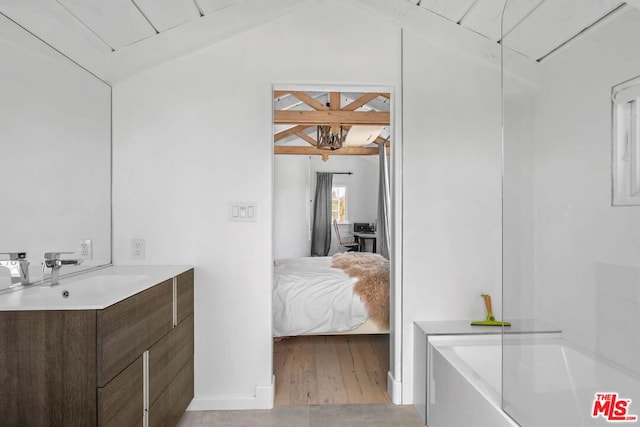 bathroom featuring vaulted ceiling, a bathtub, wood-type flooring, and vanity