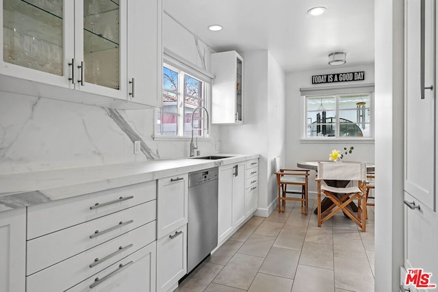 kitchen featuring white cabinetry, decorative backsplash, plenty of natural light, stainless steel dishwasher, and sink