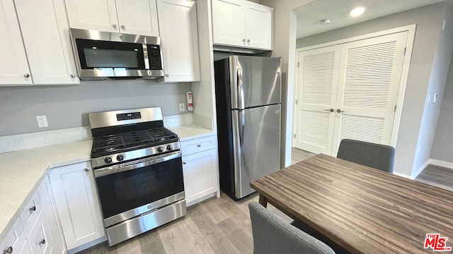 kitchen with light hardwood / wood-style floors, white cabinets, and appliances with stainless steel finishes