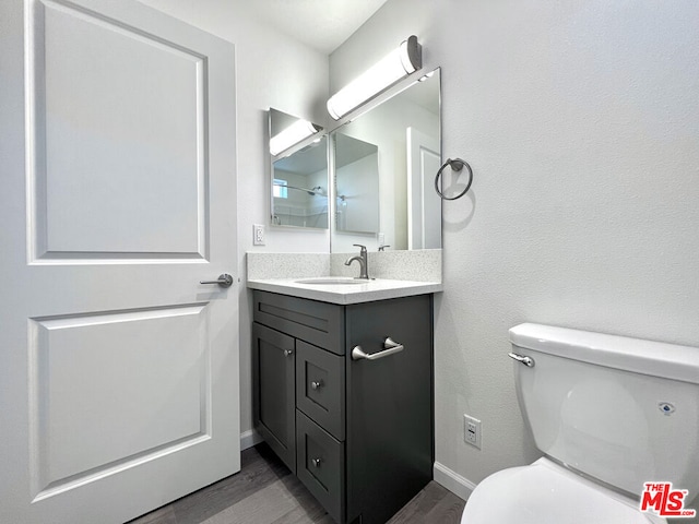 bathroom featuring toilet, wood-type flooring, and vanity