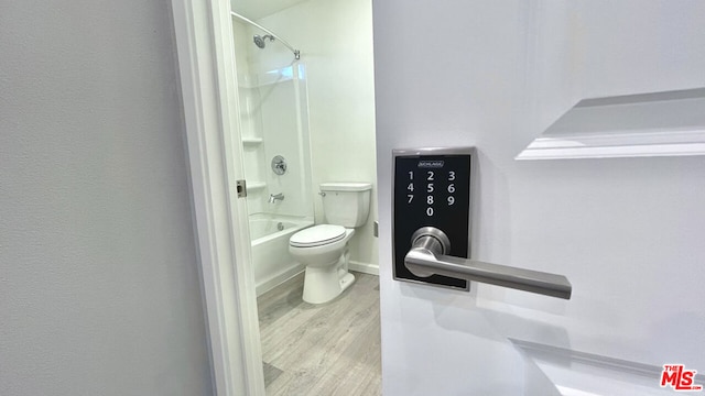 bathroom featuring toilet,  shower combination, and wood-type flooring