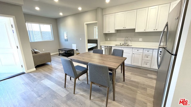 kitchen with white cabinets, appliances with stainless steel finishes, sink, and light hardwood / wood-style flooring