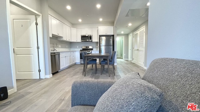 kitchen with white cabinets, appliances with stainless steel finishes, sink, and light hardwood / wood-style floors