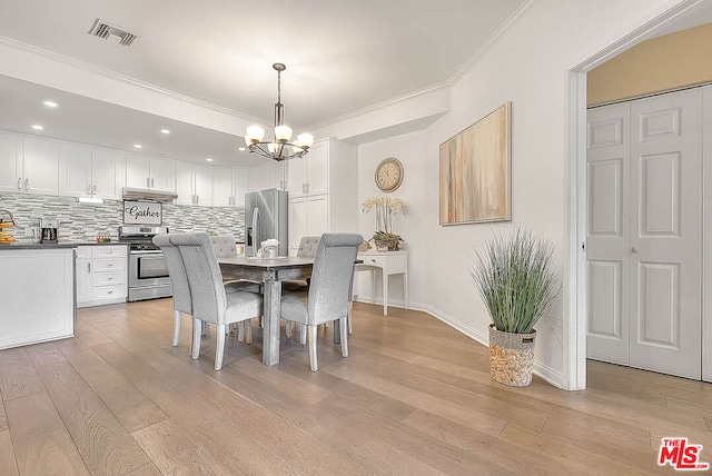 dining room with light wood-type flooring, crown molding, and a notable chandelier