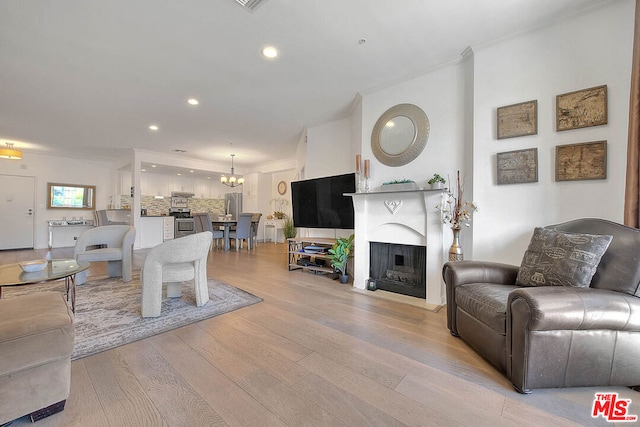 living room featuring a chandelier, light hardwood / wood-style floors, and ornamental molding