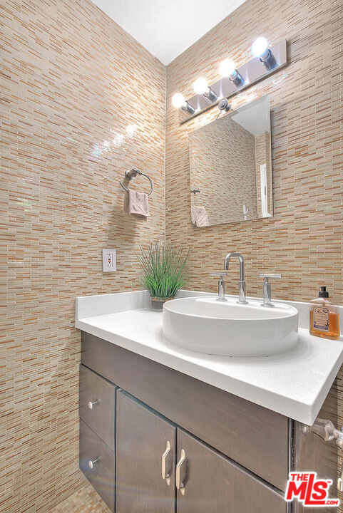 bathroom featuring vanity and tile walls