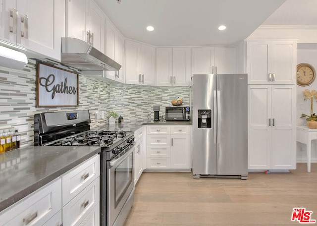 kitchen with backsplash, dark stone counters, white cabinets, light hardwood / wood-style floors, and stainless steel appliances