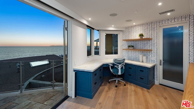 office space featuring light hardwood / wood-style floors, a water view, and built in desk