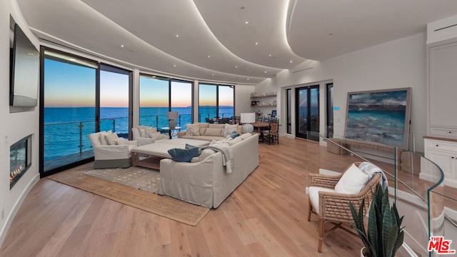 living room with expansive windows, a water view, and light wood-type flooring