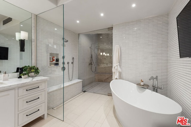 bathroom featuring tile patterned flooring, vanity, tile walls, and plus walk in shower