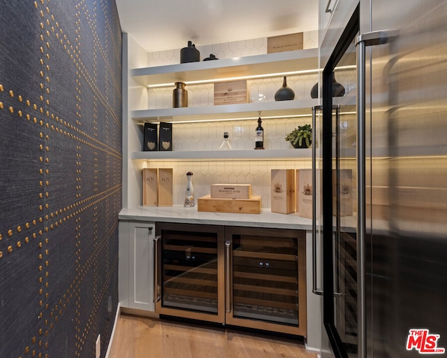 bar featuring light wood-type flooring, wine cooler, and high end refrigerator