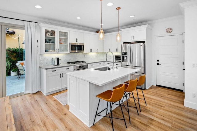 kitchen with decorative light fixtures, white cabinets, backsplash, and appliances with stainless steel finishes