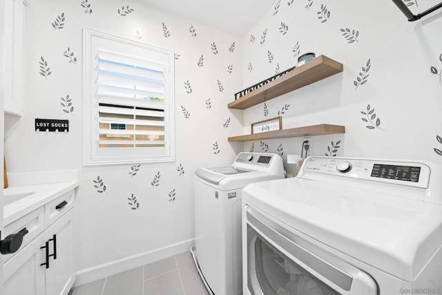 laundry area with light tile patterned floors, washer and dryer, and cabinets