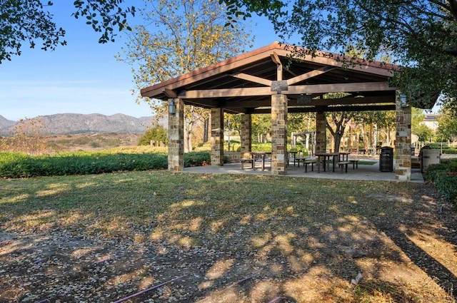 surrounding community featuring a mountain view, a lawn, and a patio