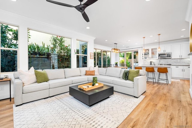 living room with ceiling fan, light wood-type flooring, and crown molding