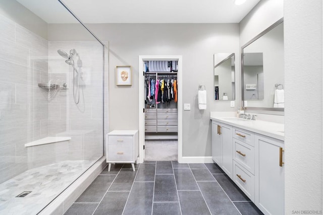 bathroom with tile patterned floors, vanity, and a tile shower