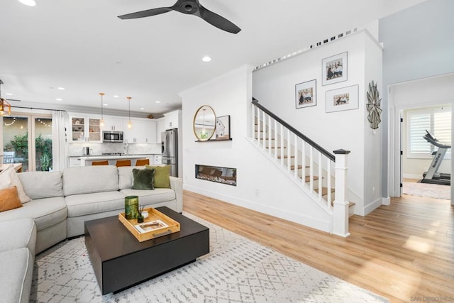 living room with light wood-type flooring, ceiling fan, a healthy amount of sunlight, and sink