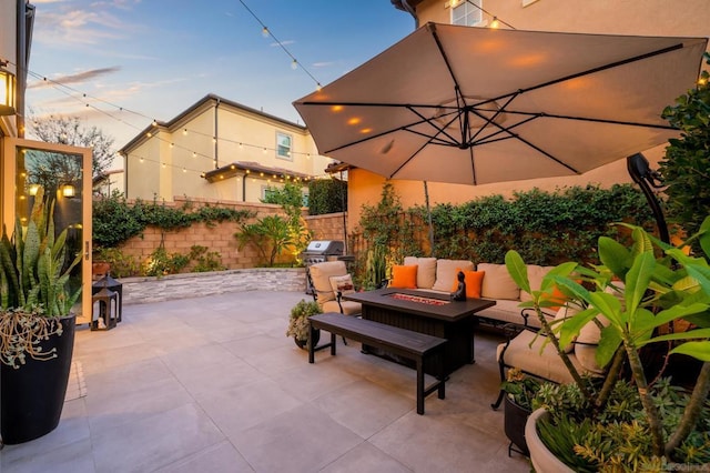 patio terrace at dusk with an outdoor living space with a fire pit and grilling area