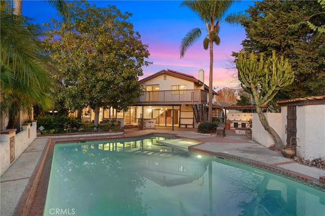 pool at dusk with a patio area