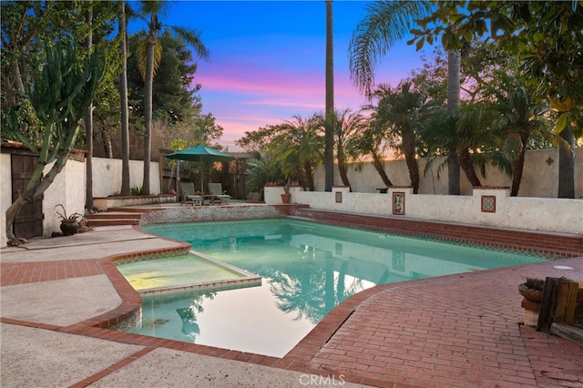 pool at dusk with a patio