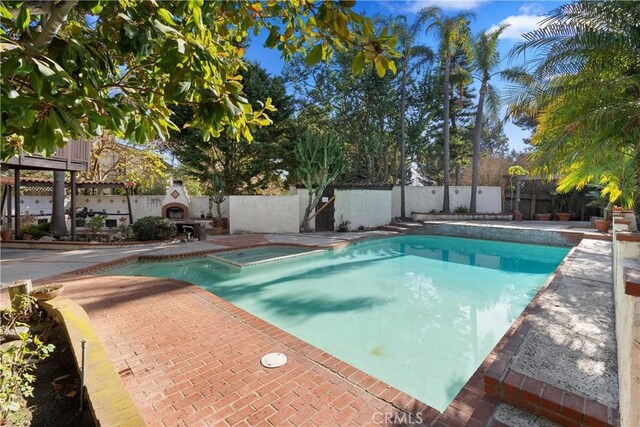 view of swimming pool featuring a patio and exterior fireplace