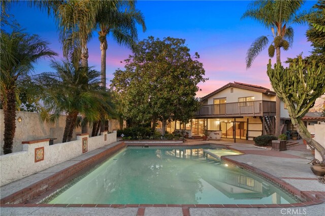 pool at dusk with a patio area