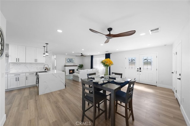 dining room with french doors, sink, ceiling fan, and light hardwood / wood-style flooring