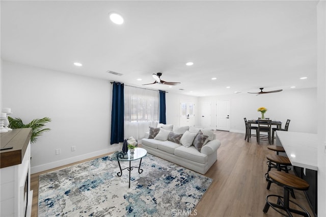 living room with light hardwood / wood-style flooring and ceiling fan